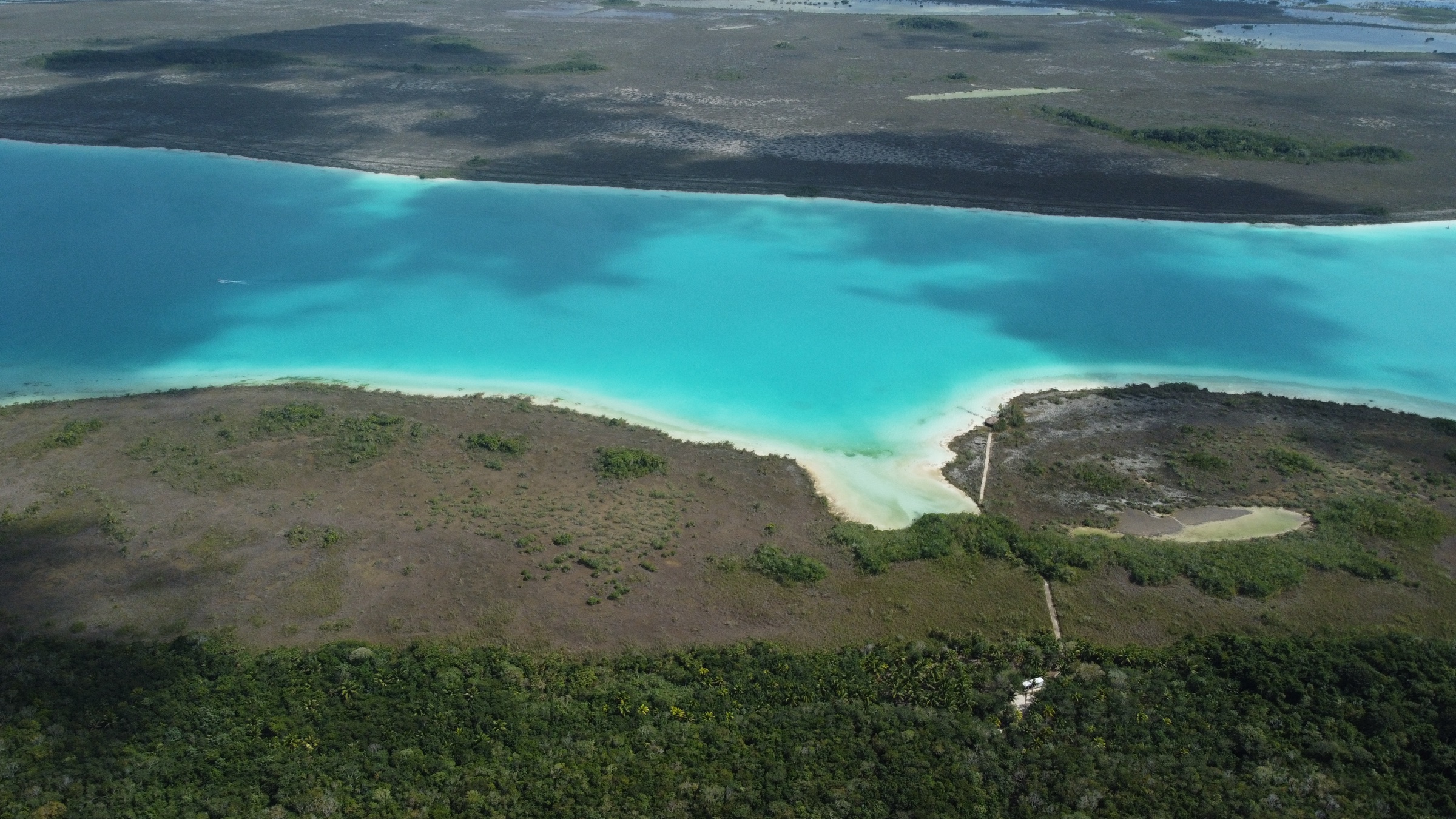 Vue aérienne de la lagune turquoise de Bacalar rejoignant la jungle.